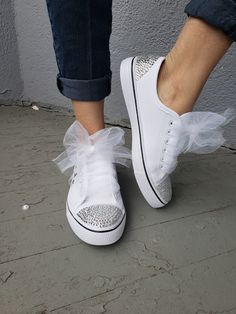 a woman's feet wearing white tennis shoes with bows