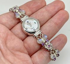 A gorgeous Precious Time sterling silver ladies wristwatch with mother of pearl dial with roman numerals. The bracelet part in a lovely butterfly and flower design, set with moonstones and amethyst. Maker/Markings: Marked 925 SILVER Condition: Very Good Used Condition. The watch works and keeps good time - Please look at photos Measurements: 7.25" long - Dial 16mm - Case 21mm Weight: 37.1g Amethyst Butterfly, Butterfly And Flower, Butterfly Flower, Butterfly Flowers, Women Wrist Watch, Design Set, Roman Numerals, Moon Stone, Sterling Silber