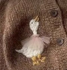 a close up of a knitted sweater with a bird decoration on the front and side