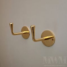 two gold handles on a white wall