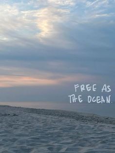 a beach with the words free as the ocean written in white on top of it