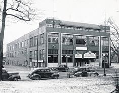 an old black and white photo of cars parked in front of a building