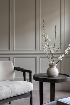 a vase with flowers sitting on a table next to a chair