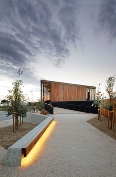 a concrete bench sitting in the middle of a walkway next to trees and bushes with lights on it