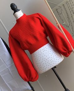 a mannequin wearing a red sweater and white skirt with polka dots on it