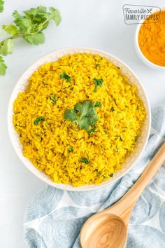 a white bowl filled with yellow rice and garnished with cilantro leaves