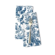 two blue and white napkins with gold forks on top of each one in front of a white background