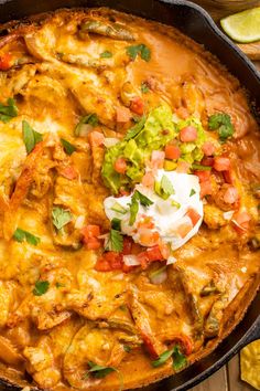 a skillet filled with mexican food and garnished with sour cream on top