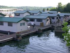 people are standing on the dock next to some houses that are built into the water