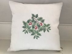 a white pillow with holly and red berries on the front is sitting on a table