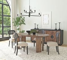 a dining room table with four chairs and a plant in the center, next to a window