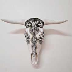 a bull's skull is adorned with intricately designed beads and silver horns are hanging on the wall