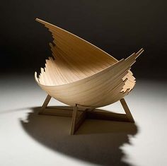 a wooden bowl sitting on top of a table next to a black wall and shadow