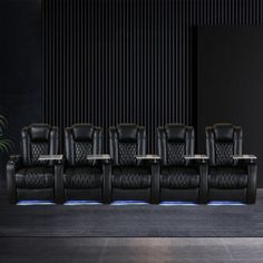 a row of black leather chairs sitting next to each other in front of a wall