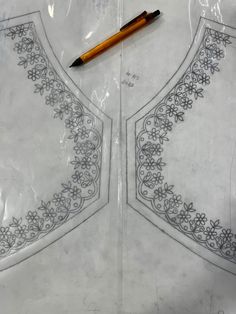 a piece of paper with an embroidered design on it next to a pen and ruler