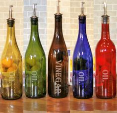 four different colored wine bottles sitting on top of a wooden table next to each other