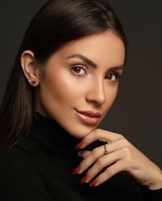 a woman with red nail polish on her nails and wearing a black turtle neck sweater