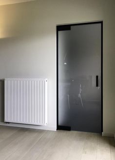 an empty room with a white radiator and glass door