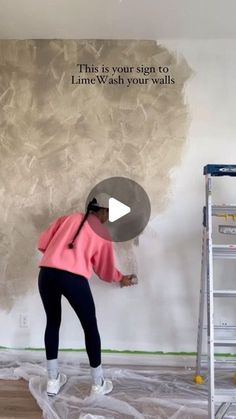 a woman is painting a wall with white paint