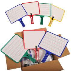 four notepads in a cardboard box with clipboards and pens on them, all lined up