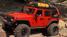 a red jeep is parked on some rocks