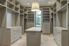 a large walk in closet with lots of drawers and cabinets on the walls, along with a chandelier hanging from the ceiling