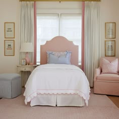 a bedroom with pink and white bedding, two armchairs and a large window