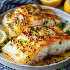 some fish on a plate with lemons and parsley