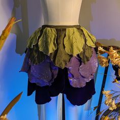 a mannequin wearing a skirt made out of leafy leaves and purple flowers