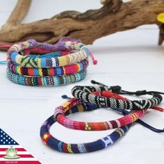 four bracelets with different colors and designs on them sitting next to each other in front of an american flag