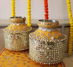 two yellow vases sitting next to each other on top of a table covered in beads