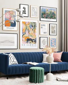 a living room filled with lots of pictures on the wall above a blue velvet couch