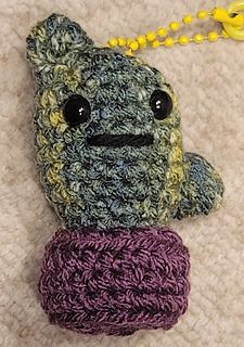 a crocheted stuffed animal with a purple and green scarf around it's neck