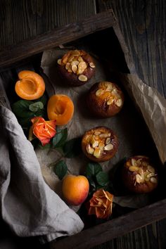 an open box filled with pastries on top of a wooden table next to peaches