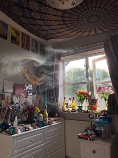 a kitchen with lots of clutter on the counter top and windows in the background