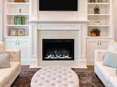 a living room filled with white furniture and a flat screen tv mounted above the fireplace