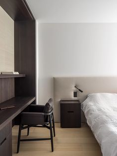 a bedroom with a bed, desk and chair next to each other in front of a white wall