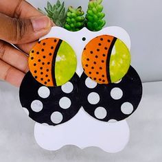 a hand is holding an ornament with polka dots and oranges on it