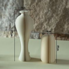 a white vase sitting on top of a table next to a smaller vase with the measurements