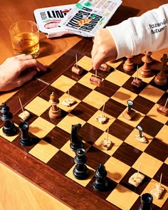 two people playing chess on a wooden table