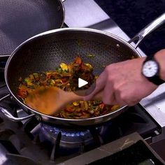 a person stirring food in a pan on the stove