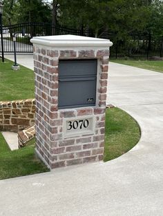 a brick mailbox sitting on the side of a sidewalk