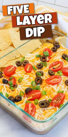 a glass casserole dish filled with cheese, olives, tomatoes and black olives