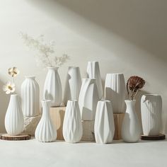 a group of white vases sitting next to each other on a counter top in front of a wall