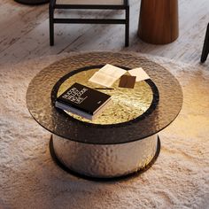 a coffee table with a book on it and two chairs in the background, along with a carpeted floor