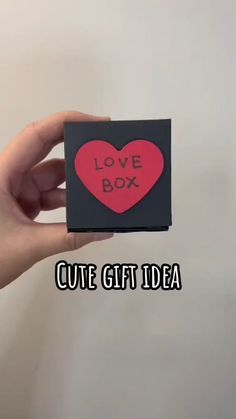 someone holding up a small card with the words love box written on it in red and black