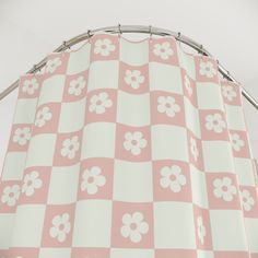 a pink and white checkerboard shower curtain with flowers on the bottom, hanging from a metal rod