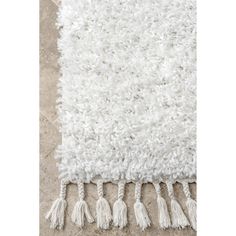 a white rug with tassels on the floor