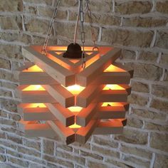 a light fixture made out of wooden planks hanging from a brick wall next to a candle holder