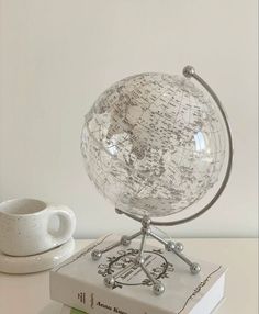 a glass globe sitting on top of a book next to a cup and saucer